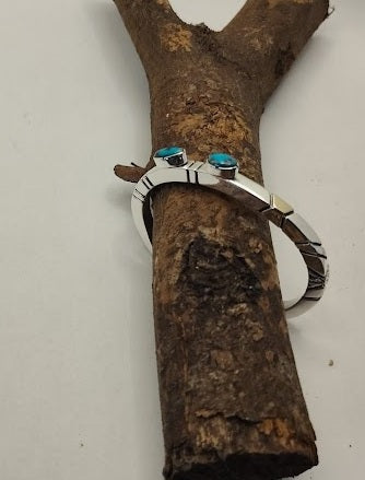 Silver ring with turquoise stones on a wooden branch